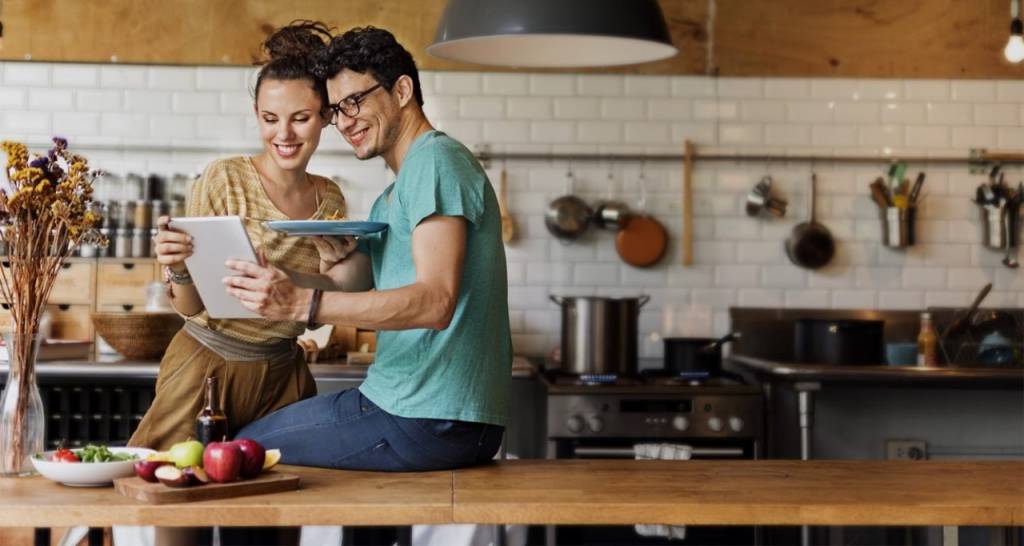 Un couple dans la cuisine regardant une tablette